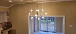 Empty beige dining room with hanging lights and sliding glass doors to a patio