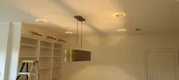 Warm-lit empty room with built-in white shelves and a hanging pendant light