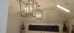 Modern lobby ceiling with hanging lantern lights, wall decor, and a black signboard.