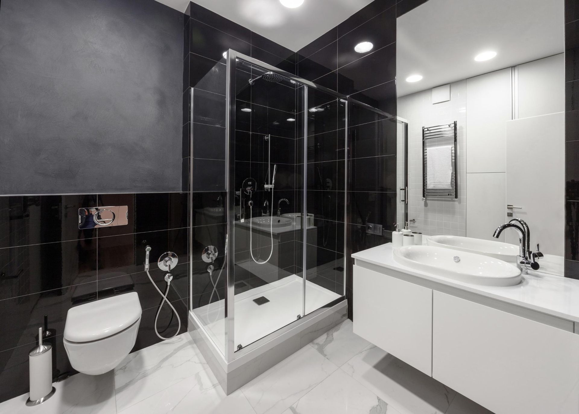 Modern black-and-white bathroom with glass shower, wall-mounted toilet, and vanity sink