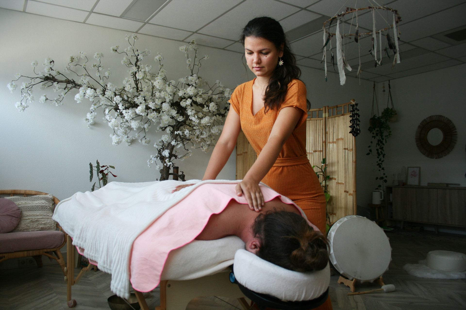 Merlinna is giving a man a fusion deep tissue massage on a table.