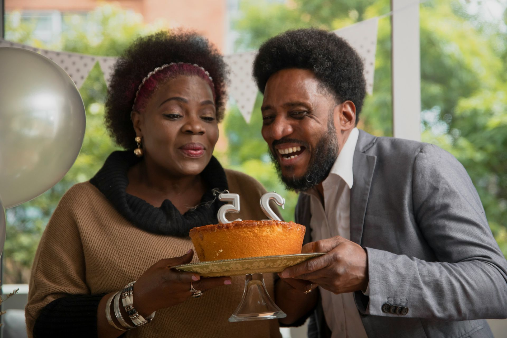 A man and a woman are blowing out candles on a birthday cake.
