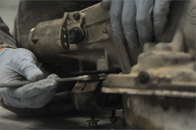 Gloved hands using a wrench to repair machinery in a workshop.