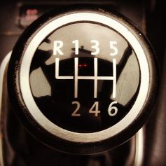 Close-up of a manual car gear shift pattern with reverse and six forward gears