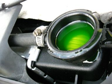 Open radiator cap with bright green coolant visible inside the reservoir