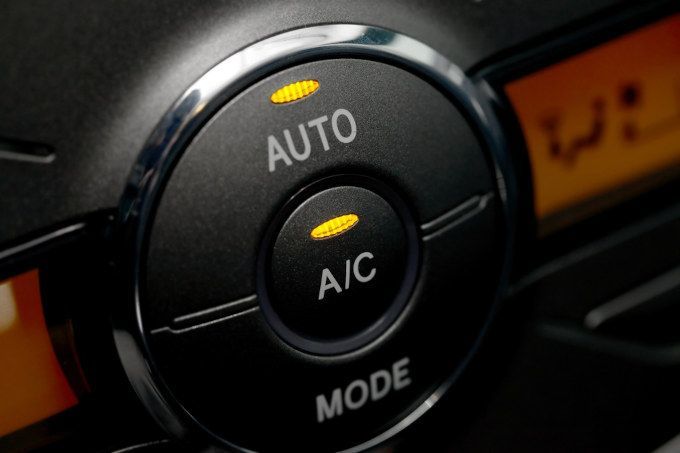 Close-up of car climate control dial with AUTO, A/C, and MODE labels, lit in orange.
