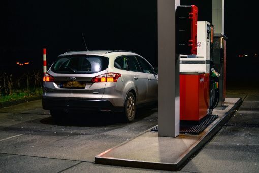 Silver SUV parked at a red-and-white gas pump at night