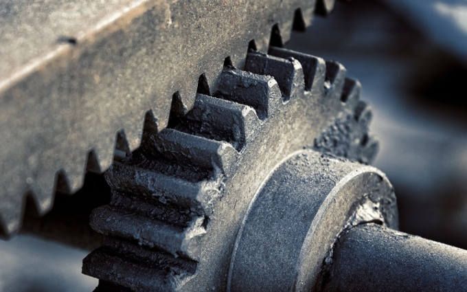 Close-up of interlocking metal gears in a machine, covered with dark grease.