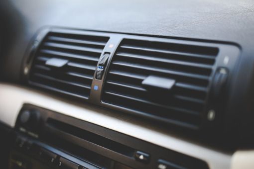 Car dashboard air vents with a central control knob, in black and silver trim