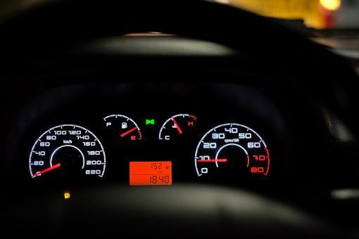 Car dashboard at night with illuminated speedometer, gauges, and orange digital display