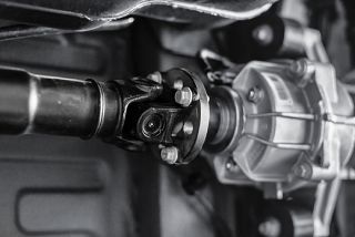 Close-up of a metal drive shaft and universal joint connected to a gray gearbox component
