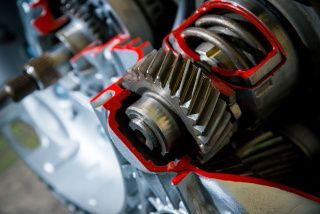Close-up of metal gears coated in red lubricant inside a mechanical assembly