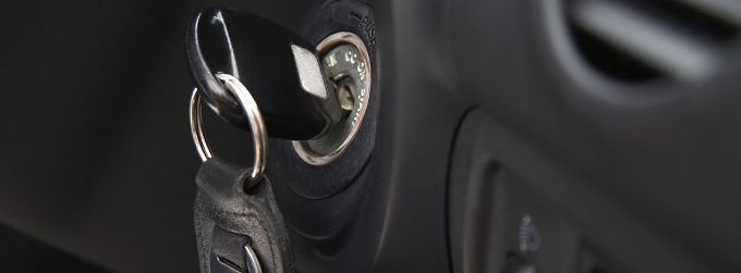 Car keys inserted in a car ignition beside a dashboard vent