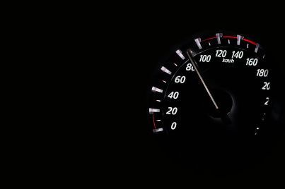 Car speedometer at night, needle near 60 mph on a black dashboard