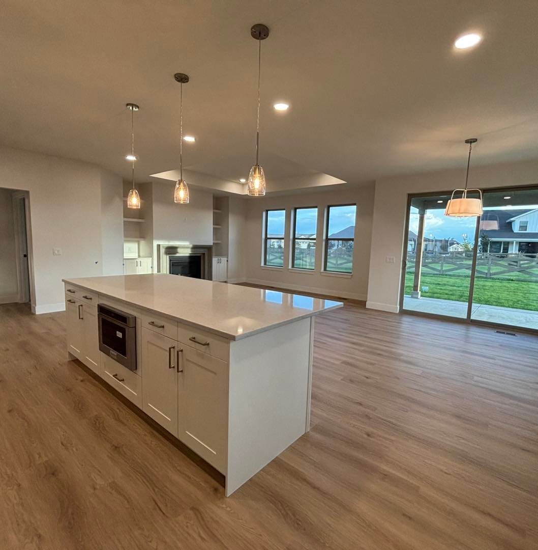 Modern kitchen with white island, hardwood floors, and sliding glass door to a yard.