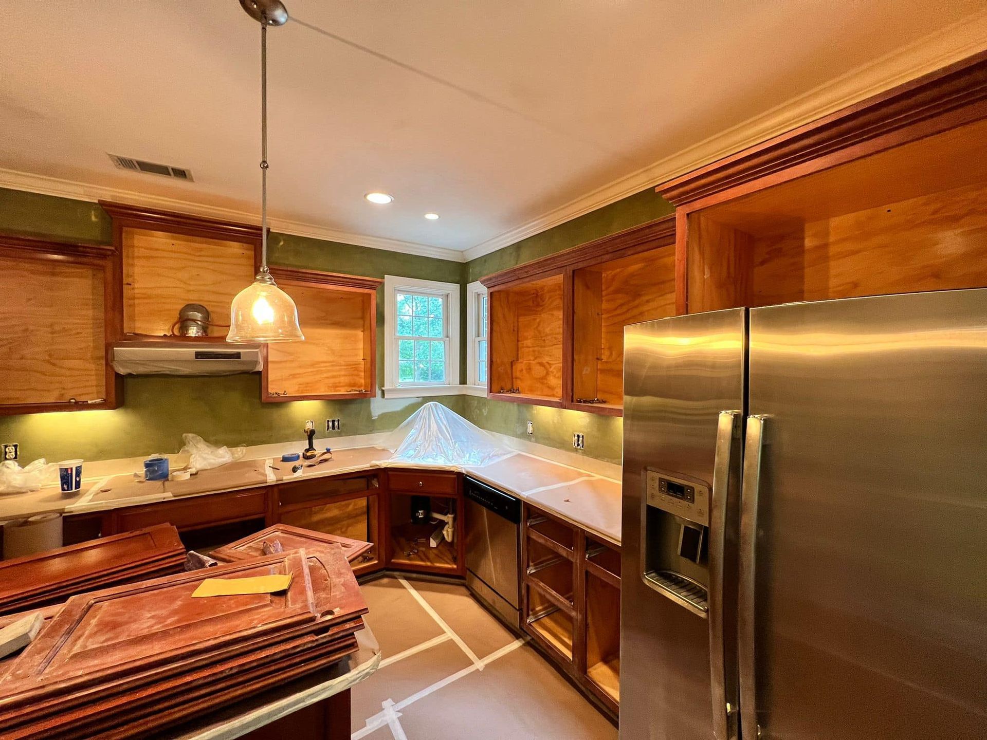 Warm wood kitchen with stainless steel fridge, dark counters, and pendant light over island.