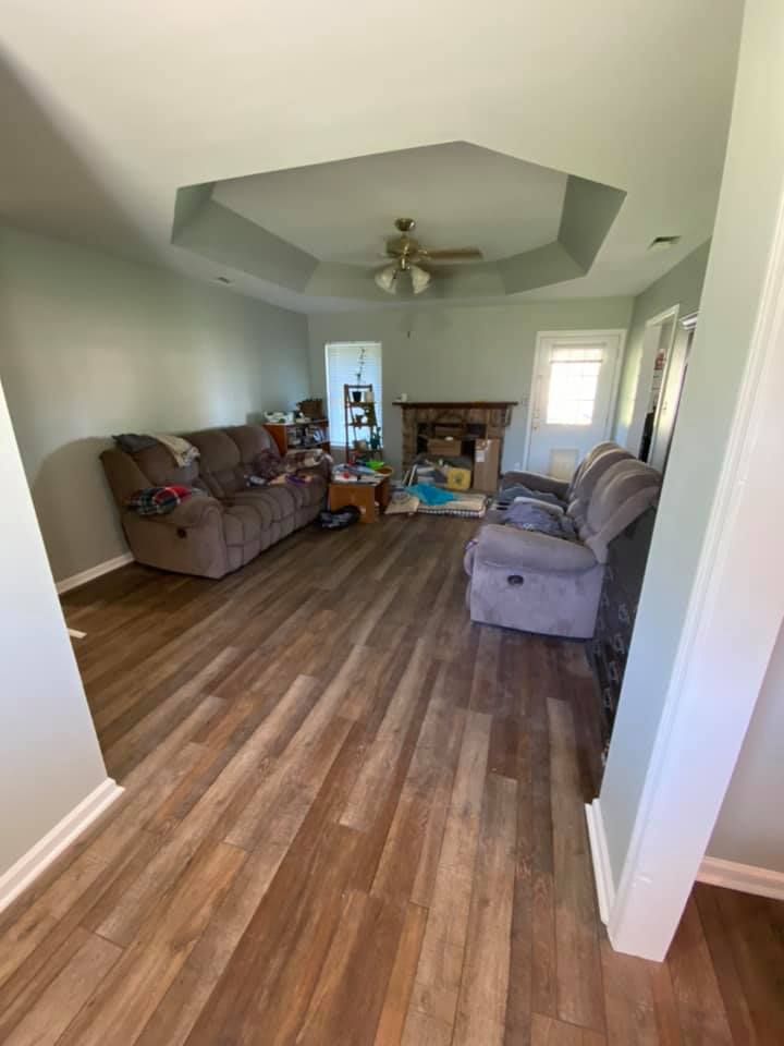 Living room with wood-look flooring, gray and brown sofas, ceiling fan, and octagonal tray ceiling