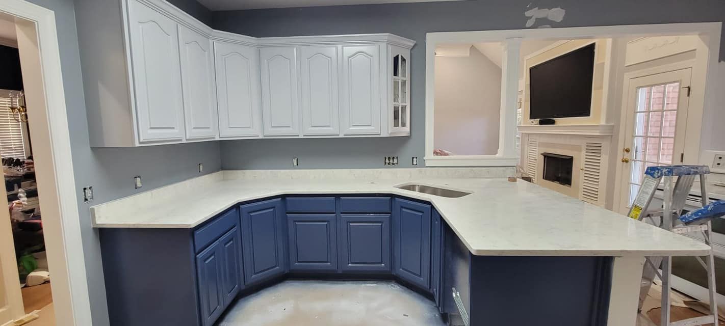 Blue and white kitchen cabinets with black countertops and a curved peninsula under renovation