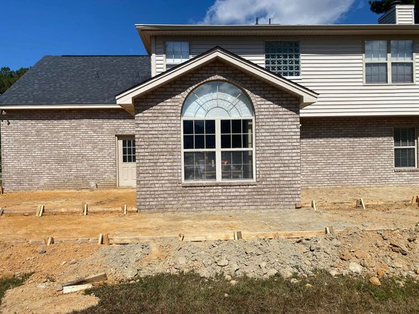 Brick house exterior with a large arched window and unfinished landscaping in front