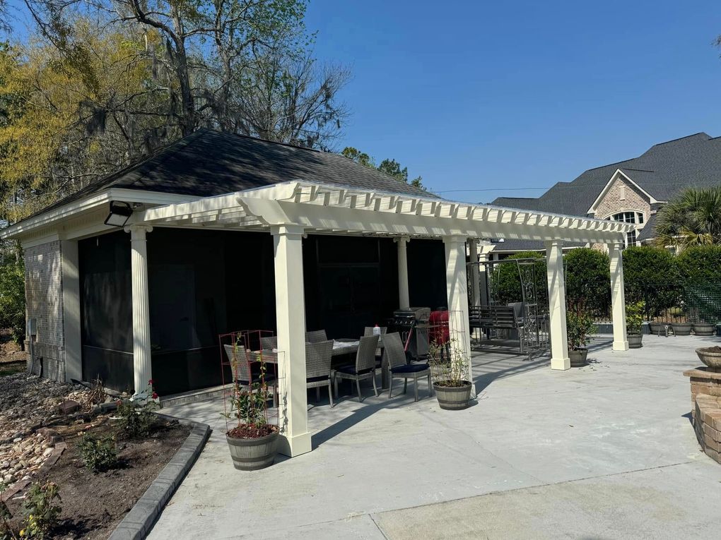 Covered patio with white columns, outdoor seating, and potted plants beside a stone walkway