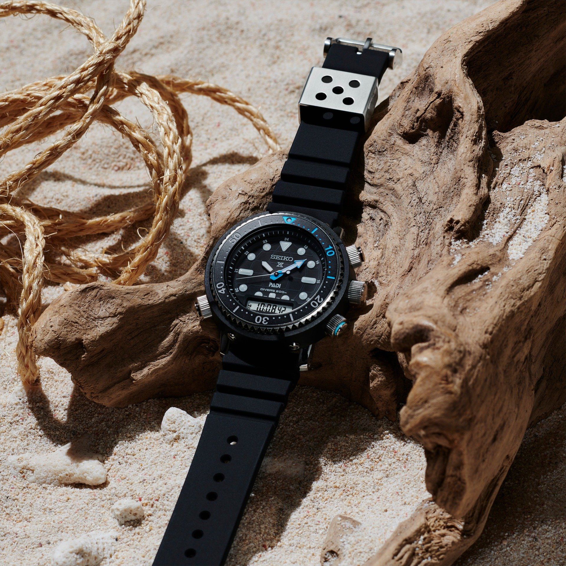 Een zwart horloge ligt op een stuk drijfhout