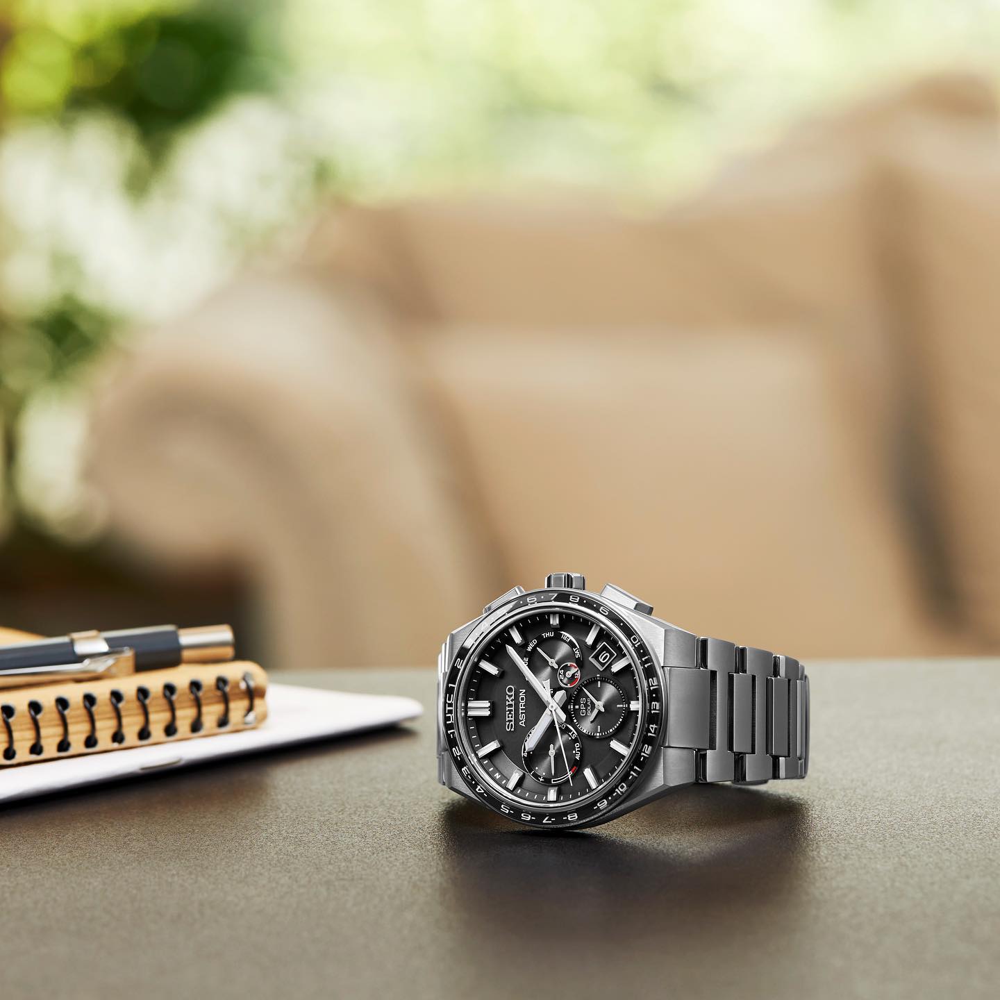 Een horloge ligt op een tafel naast een notitieboekje