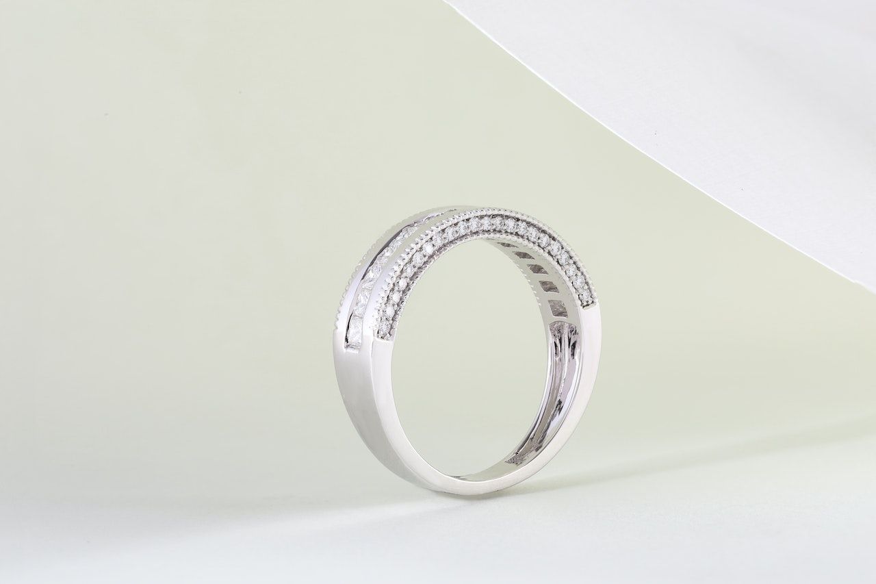 Een witgouden ring met diamanten ligt op een wit oppervlak.