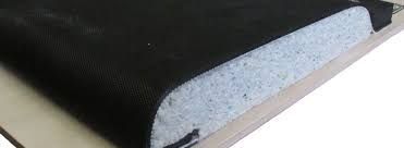 Gros plan d'un bord de tissu noir avec un matériau spongieux bleu clair en dessous, reposant sur une surface beige.