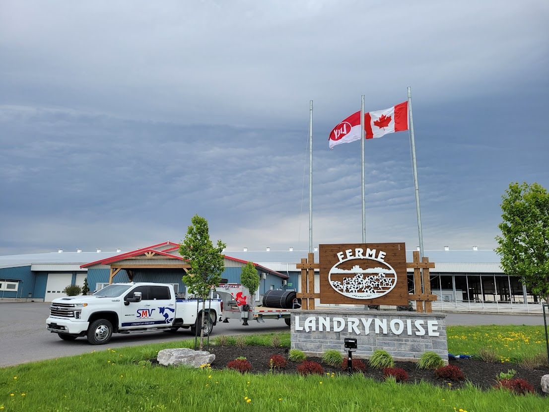 A white truck towing a trailer near a sign for