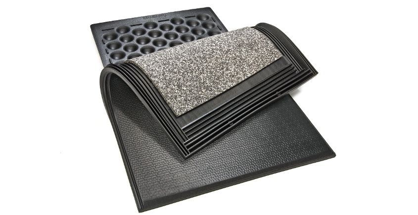 Une pile de trois tapis en caoutchouc noir. L'un a une surface supérieure mouchetée de gris et de noir, l'autre est perforé et le troisième est plein.