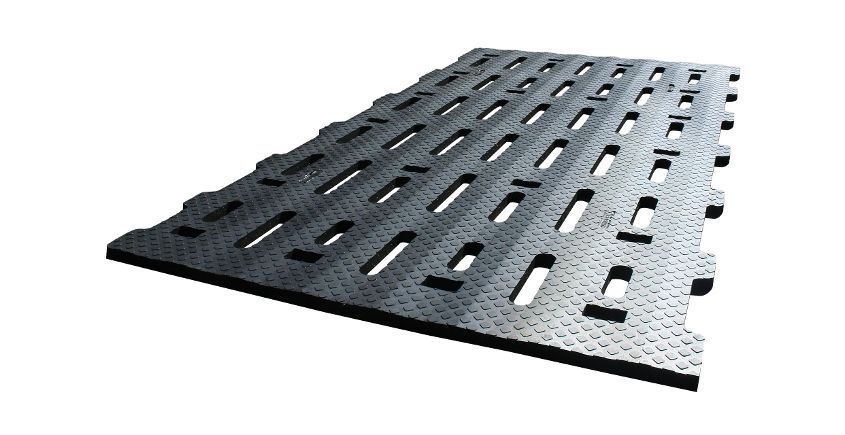 Tapis de protection de sol noir et robuste, avec ouvertures rectangulaires fendues et bords emboîtables. Pour chaussées temporaires ou accès sur sol meuble.