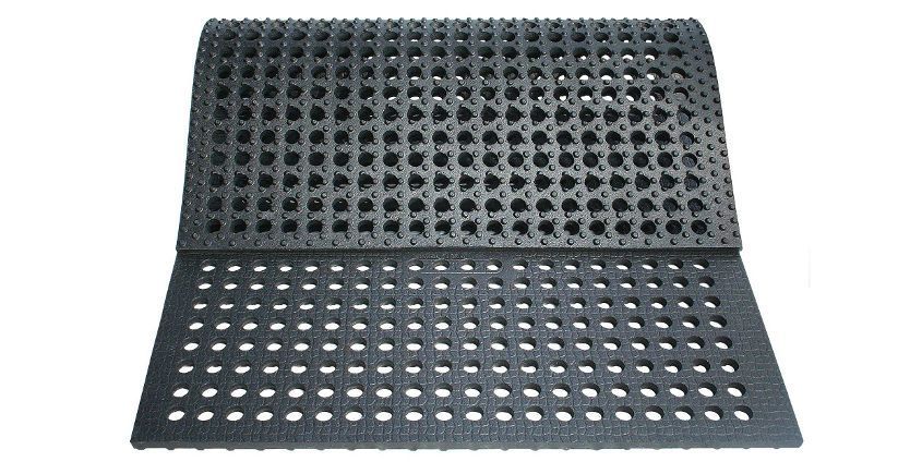 Tapis en caoutchouc noir avec trous perforés ; une moitié repliée.