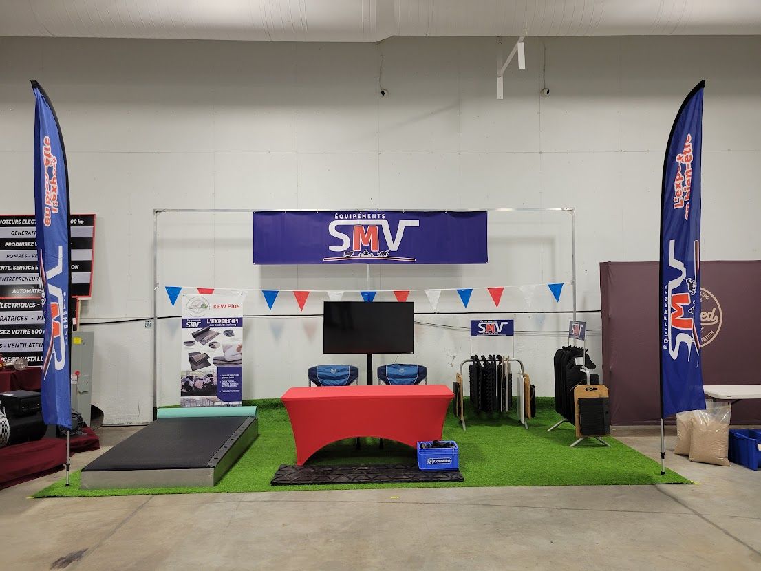 An event display with a red table and TV screen, blue flags, and artificial grass. The logo