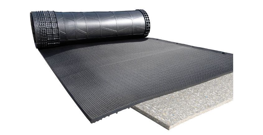 Roll of black drainage composite with a rolled-out section and a white foam board, likely for construction or landscaping.