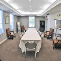 Conference room with long table, chairs, and a wall-mounted TV in a bright office setting