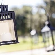 Black metal lantern hanging outdoors with a blurred green park background