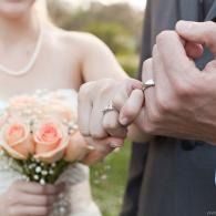 Bride and groom holding hands, bride with peach bouquet outdoors