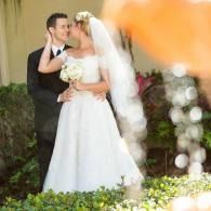 Bride and groom embracing outdoors, bride in white dress and veil holding bouquet