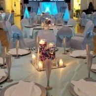 Round banquet tables with white chairs and blue chair sashes in a softly lit event hall.