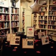 Library display with bookshelves, star balloon, and framed signs on a table covered in black fabric.