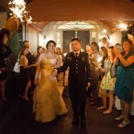 Bride and groom walking through an applauding crowd at a warmly lit wedding reception