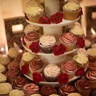 Tiered display of decorated cupcakes in red, white, and chocolate frosting at a dessert table