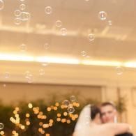 Blurred couple embracing under warm lights with floating bubbles indoors