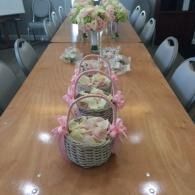 Long conference table with pink flower baskets arranged down the center