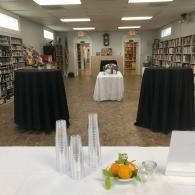 Library event space with cocktail tables, bookshelves, and a front display table.