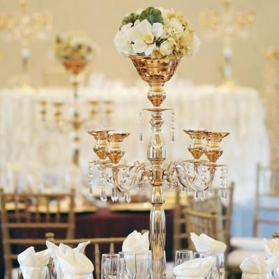Elegant gold candelabra centerpiece with white flowers on a decorated banquet table