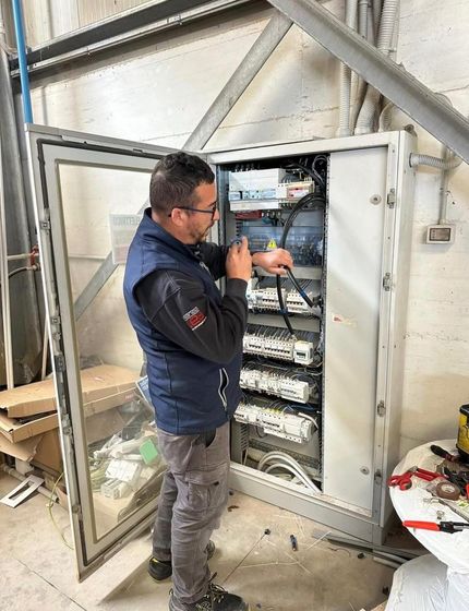 Tecnico al lavoro all’interno di un quadro elettrico aperto in un’officina.