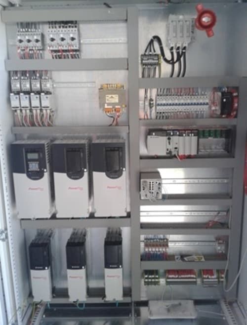 Quadro elettrico di controllo con interruttori automatici, relè e cablaggio all'interno di un armadio metallico.