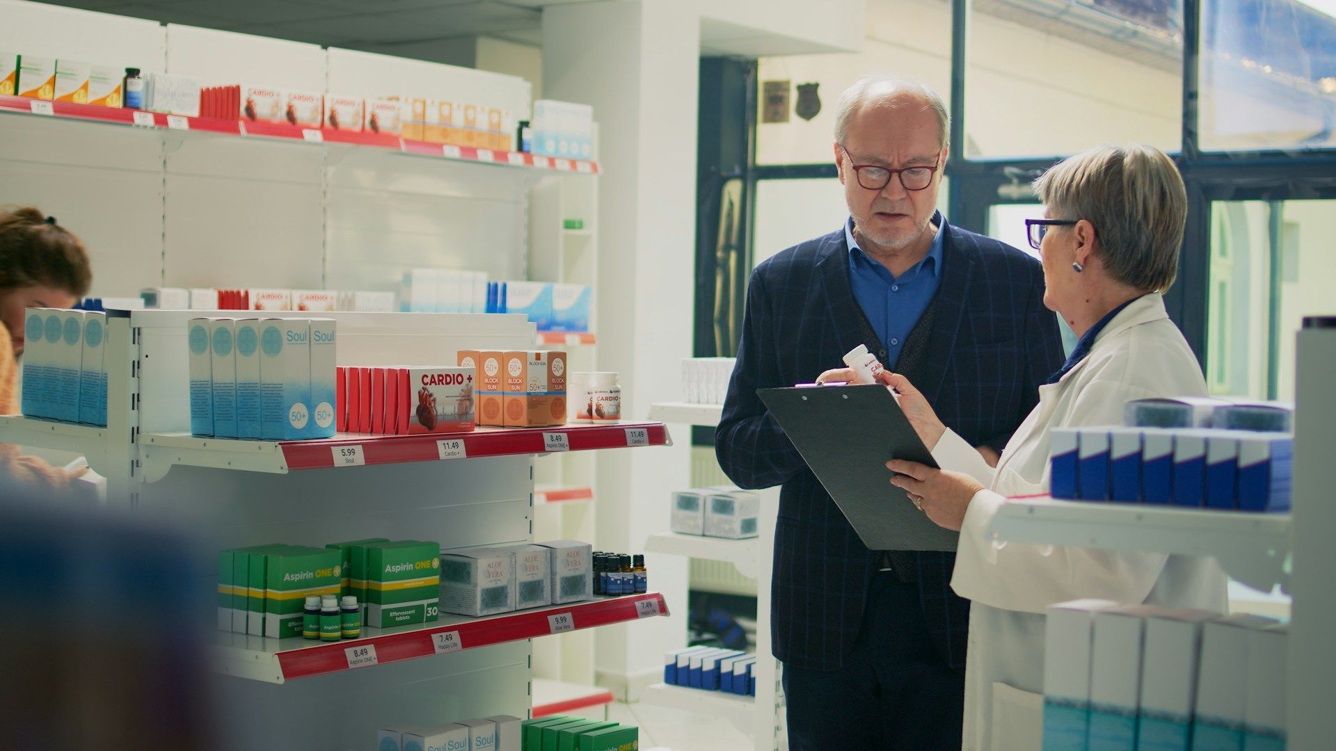 A man and a woman are standing in a pharmacy looking at a clipboard.