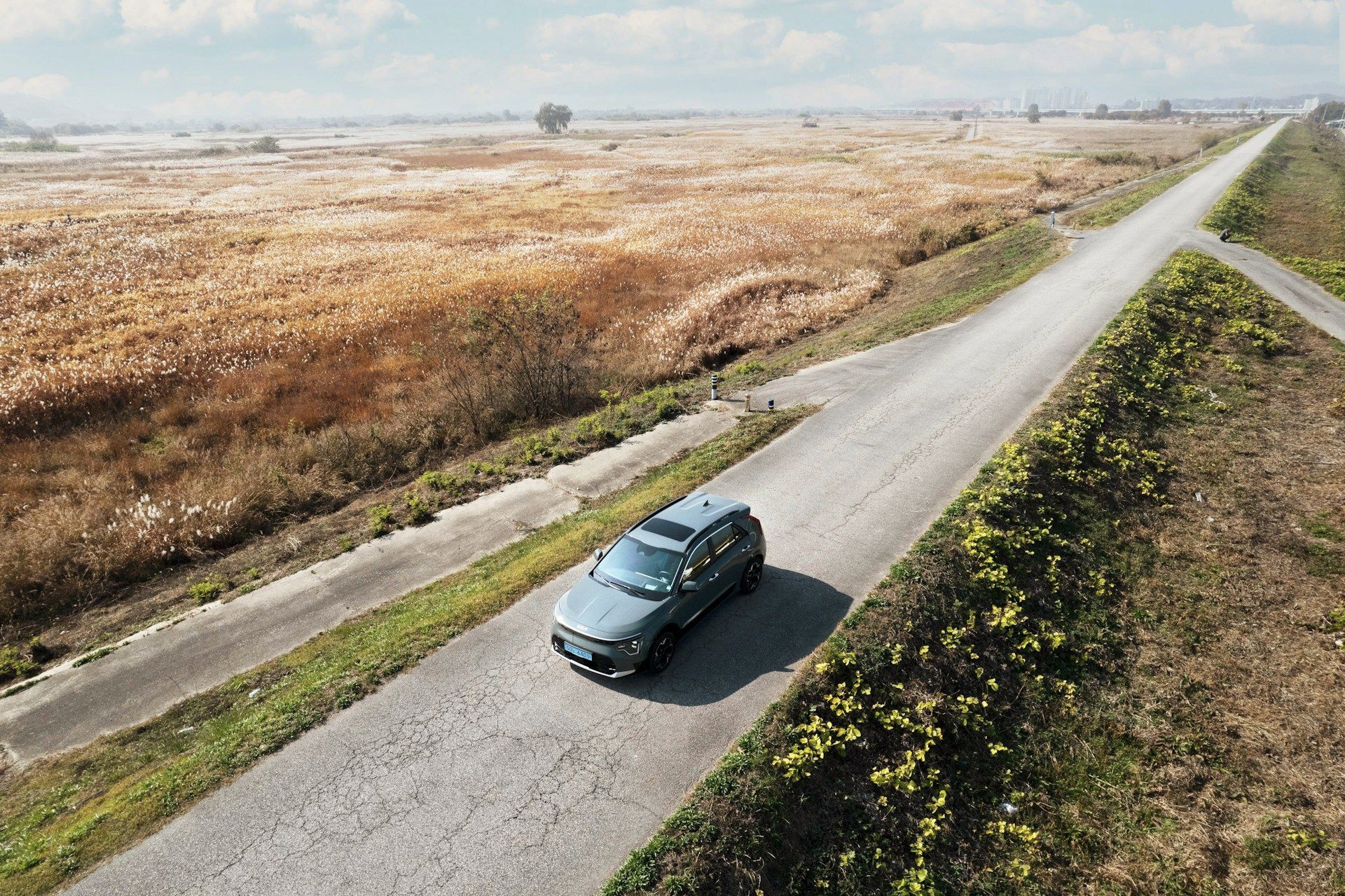 An aerial view of a car driving down a dirt road.